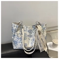 Detalle de bolso tote de lona con bordado floral y elegante correa de cadena de metal - Azul
