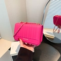 Bolso magenta con rayas verticales y correa de cadena dorada sostenido a mano - Rosa Rojo