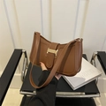 Bolso de hombro vintage de cuero marrón con cierre dorado mostrado en mano sobre fondo minimalista - Marrón