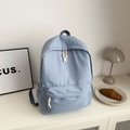 Minimalist light blue campus backpack in a clean aesthetic setting with front zipper pocket - Blue