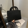 Bolso bandolera negro mate con asa circular calada y elegantes detalles dorados - Negro