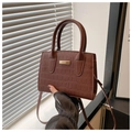 Détail du sac à main marron à motif crocodile avec boucle dorée et doubles poignées - Café