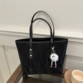 Black crinkled tote bag with leather handles and white plush charm on a wooden table - Black With Rabbit Pendant