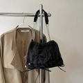 Black pleated tote bag with bow detail and silver chain strap shown on coat hanger - Black