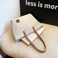 Grande borsa tote in tela crema con cinturini in pelle marrone e logo sul divano - Bianco Sporco