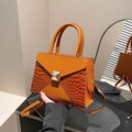 Brown crocodile embossed tote bag with a square gold buckle shown being held - Brown
