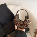 Mini hobo bag with leopard print and gold hardware held by hand in a chic indoor setting - Brown