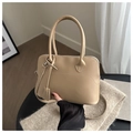 Dettaglio della borsa tote beige in pelle con cuciture curve e ciondolo abbinato - Cachi