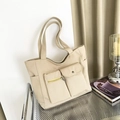 Beigefarbene Canvas-Einkaufstasche mit Funktionstaschen und Doppelriemen auf Stuhl - Khaki