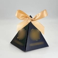 Nahaufnahme der pyramidenförmigen schwarzen Pralinenschachtel mit goldener Schleife - Schwarz