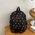 Close-up of black floral nylon mini backpack with zipper pockets on wooden surface - Little Floral / Black