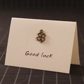 Ciondolo quadrifoglio in bronzo vintage su un biglietto d'auguri con scritte - Quadrifoglio