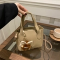 Detalle de bolso de mano en cuero beige con colgante de peluche y hebillas doradas - Con Colgante / Caqui
