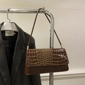 Detail of dark brown vintage shoulder bag with golden crocodile texture on the flap - Coffee