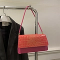 Detail of coral pink underarm bag with crocodile embossed flap and gold hardware - Pink