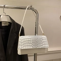 Detail of white crocodile embossed texture on a minimalist retro shoulder bag - White