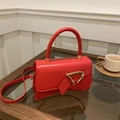 Close-up of red leather handbag with elegant triangular gold buckle and handle - Red