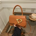 Detail of caramel leather handbag featuring a decorative bow and gold D-shaped buckle - Tan