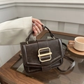 Borsa a tracolla retrò marrone scuro con fibbia dorata in un ambiente da caffè - caffè