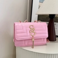 Pink quilted shoulder bag with gold double S logo and tassel on a white pedestal - Pink