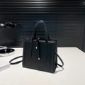 Minimalist black tote bag with matte texture and decorative straps in a modern setting - Black