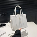Chic white structured crossbody bag with gold hardware and drawstring detail on desk - White