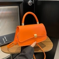 Elegante bolso baguette naranja brillante con hebilla dorada y asa sobre madera - Naranja