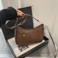 Detalle de bolso bandolera vintage marrón oscuro de cuero sintético con hebilla dorada - café