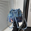 Detail of blue denim bucket bag with distressed star patches and leather drawstring closure - Star - Rainbow