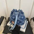 Detalle de bolso bucket de denim azul con estrellas blancas, flecos y cordón de cuero - Pentagrama Blanco