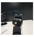 Close-up of black quilted mini bag with oversized leather bow and gold chain strap - Black
