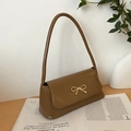 Détail du sac baguette en cuir PU marron caramel avec boucle noeud dorée sur bois - Kaki