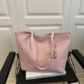 Grand cabas rose avec imprimé monogramme M et breloque dorée sur un fauteuil chic - Rose