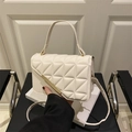 White quilted crossbody bag with gold accents and detachable strap on minimal background - White
