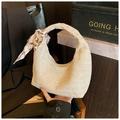 Detail einer halbmondförmigen Strohtasche mit Seidenschal und beiger Webstruktur - Gebrochenes Weiß