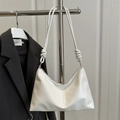 Minimalist white PU leather hobo shoulder bag with artistic knotted strap detail on a rack - White