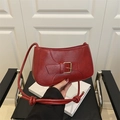 Close-up of a red shoulder bag featuring a golden metal buckle and knotted strap detail - Red