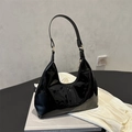 Bolso hobo vintage de charol negro con herrajes dorados sobre una pila de libros - Negro