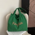 Green nylon tote bag with orange letter print and drawstring design on a white chair - Light Green