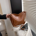Chic brown leather bucket tote bag with adjustable strap in a stylish minimal setting - With Pendant / Brown