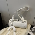 White cylindrical baguette bag with oversized bow charm and silver hardware accents - White