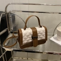 Chic quilted white handbag with brown trim and metal clasp on a lifestyle display - White and Brown
