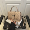 Beige quilted small crossbody bag with silver buckle and chain strap on a black chair - Khaki
