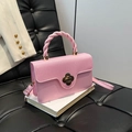 Petit sac rose avec poignée tressée et fermoir fleur en métal posé sur un livre - Rose