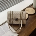Beige gewatteerde crossbodytas met gouden kettingriem op een houten bureauzetting - Khaki