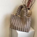 Taupe faux fur handbag featuring a textured vertical stripe design and pompom handle - Brown