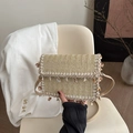 Beige woven crossbody bag with bohemian shell charms and lace trim on a cozy chair - Khaki
