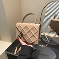 Elegante bolso acolchado beige con hebilla de cadena dorada en una toma de mano de estudio - Caqui