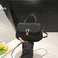 Black handbag with sequined flap and golden buckle on a white pedestal display - Black