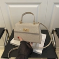 Bolso de lentejuelas color champán con cierre metálico y correa en una silla - Dorado